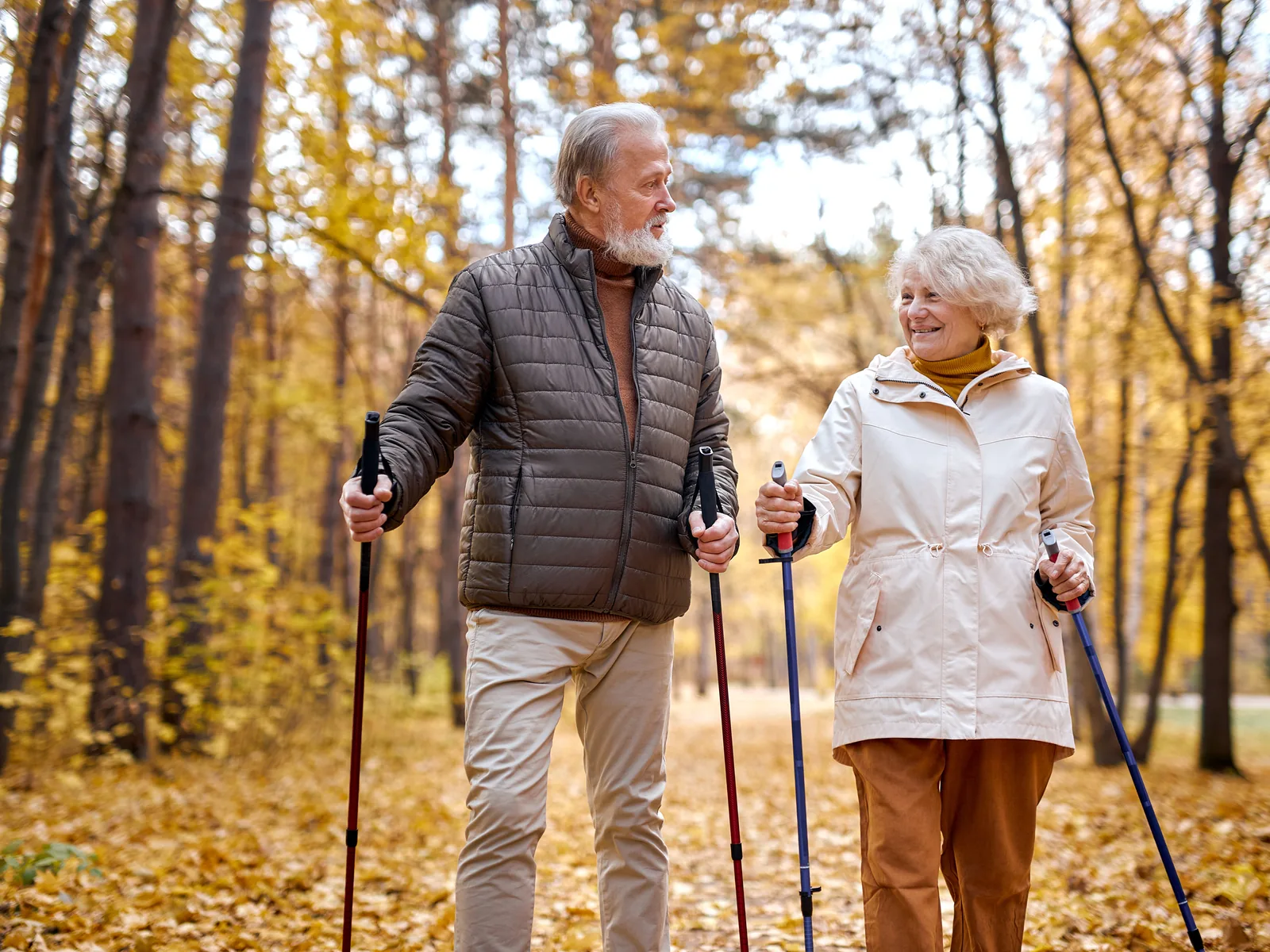 Engegefühl bei Polyneuropathie: aktives Seniorenpaar beim Nordic Walking im Herbstpark